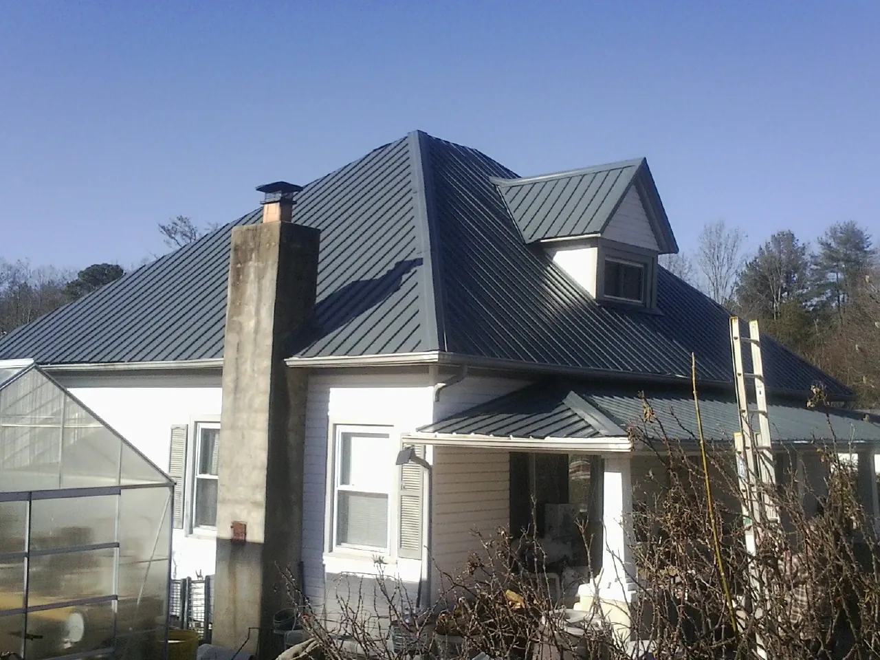 Dark blue standing seam metal roof on a white farmhouse with dormer — Slate & Tile Roof Repair by Roofing Brothers in Cowlesville
