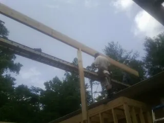Carpenter setting a ridge beam over a new addition frame — Ice Dam Removal by Roofing Brothers in Cowlesville