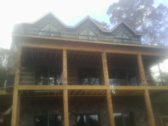Dormers and porch framing on a large log home under construction — Roof Coating work by our crew in Cowlesville