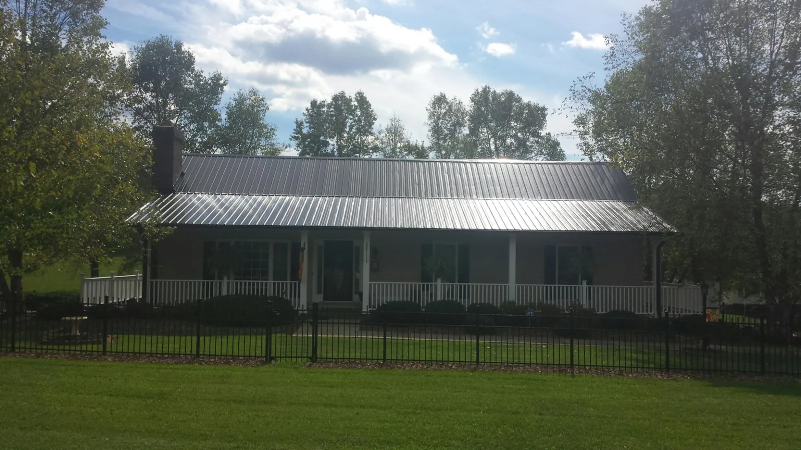 Gray metal roof on a brick ranch with a full width front porch — Gutter Guard Installation work by our crew in Cowlesville