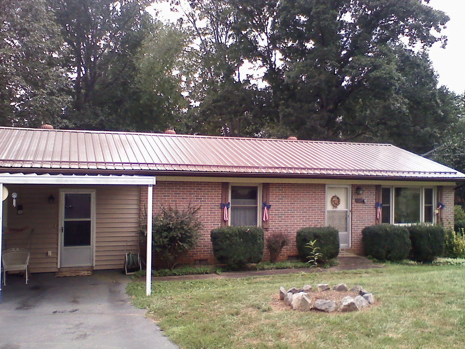 Bronze metal roof and carport on a brick ranch home — Roof Repair work by our crew in Cowlesville