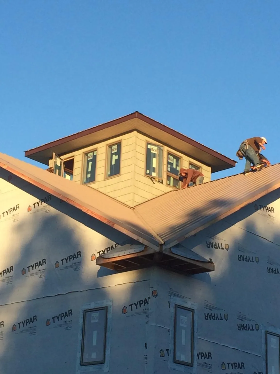 Roofers working around a rooftop cupola on a new metal roof at sunset — Roof Waterproofing in Cowlesville by Roofing Brothers